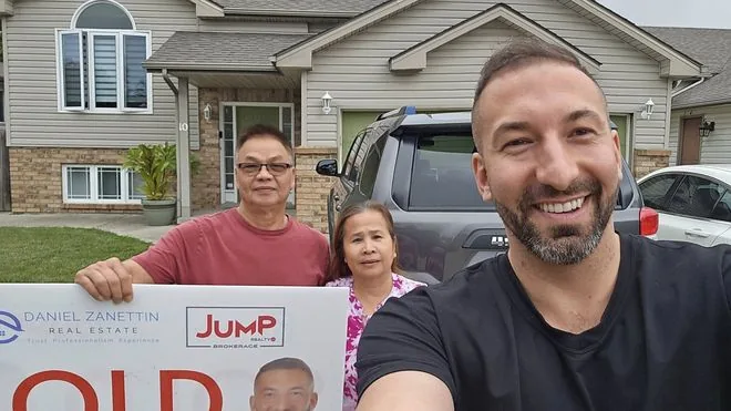 Happy sellers in front of their sold home with Daniel Zanettin